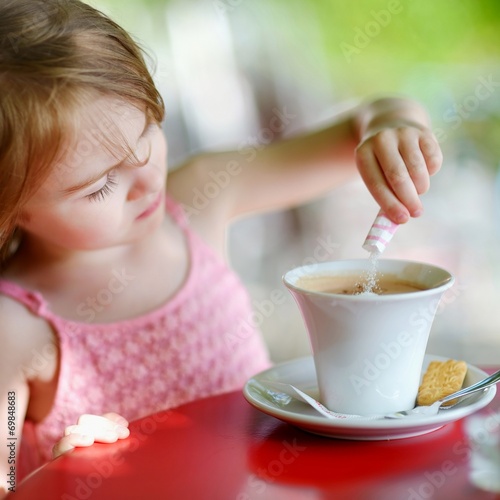 Little girl pouring sugar into hot chocolate