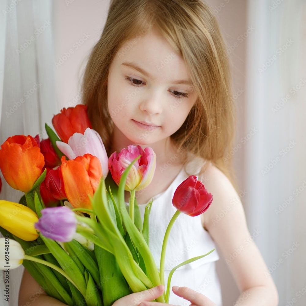 Adorable little girl with tulips by the window