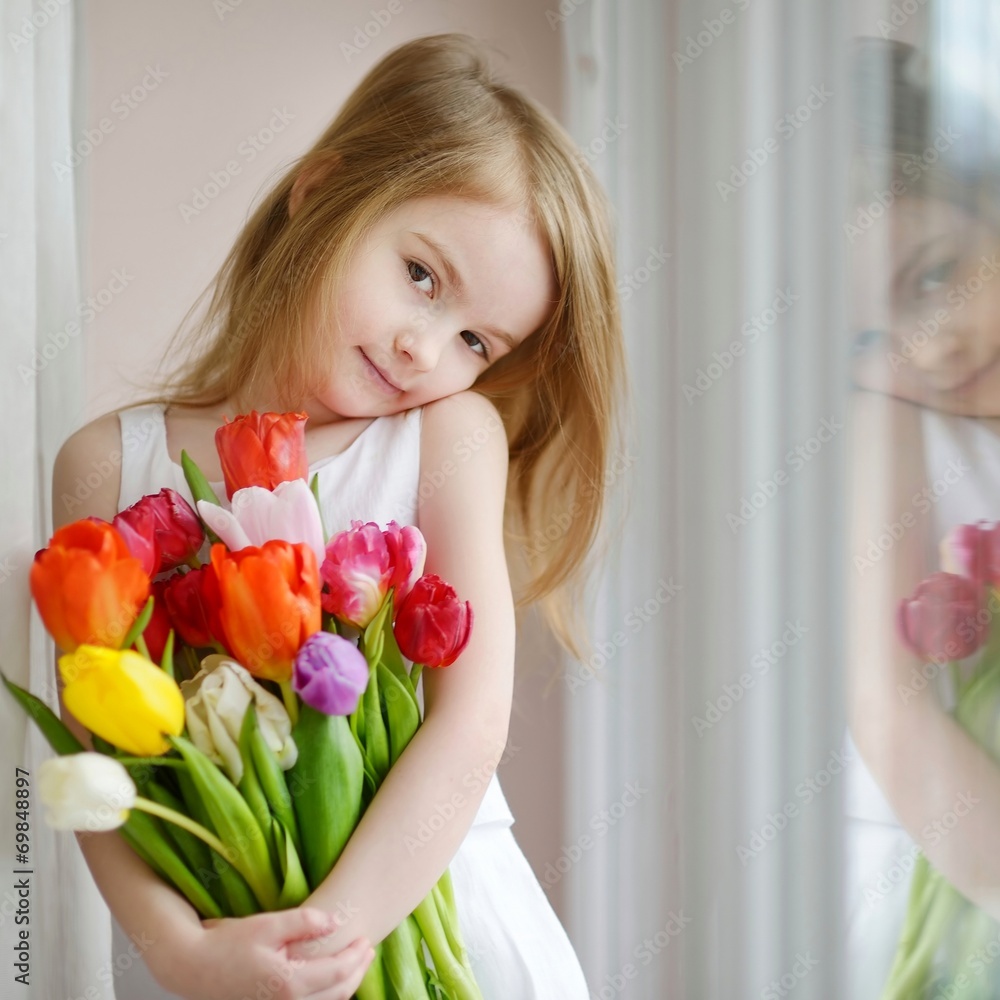 Adorable little girl with tulips by the window Adorable little girl with tulips by the window