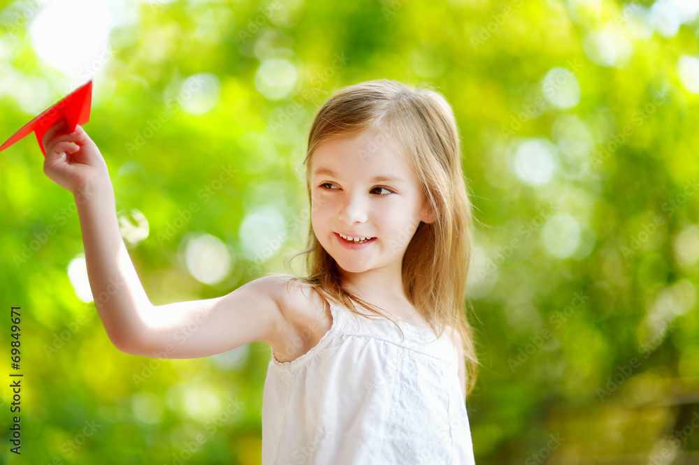Adorable little girl holding a paper plane Adorable little girl holding a paper plane