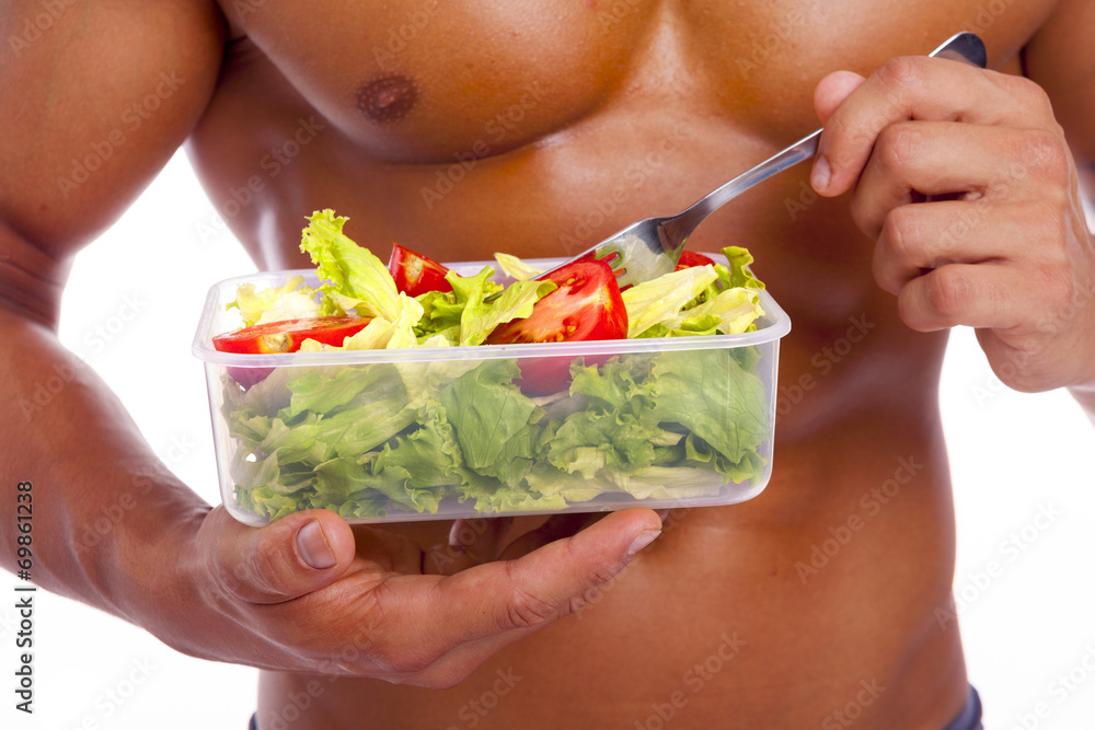 Close-up of a muscular man holding a bowl of fresh salad on a wh Close-up of a muscular man holding a bowl of fresh salad on a wh