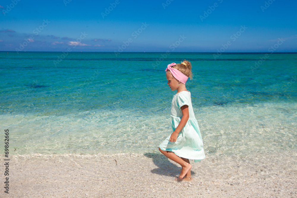 Cute little girl playing in shallow water at white beach Cute little girl playing in shallow water at white beach