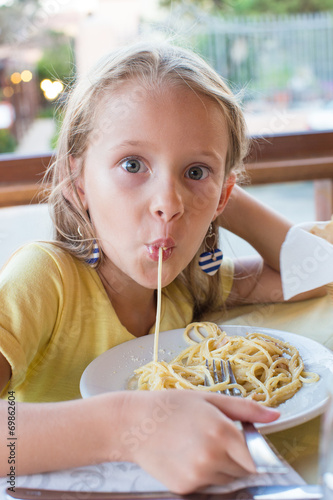 Obraz na płótnie Adorable little girl eating spaghetti in outdoors restaraunt w salonie