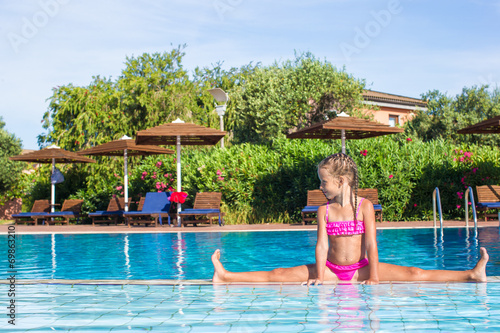 Adorable happy little girl in the swimming pool sitting on the