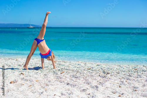 Photo Adorable little girl making wheel on tropical white sandy beach