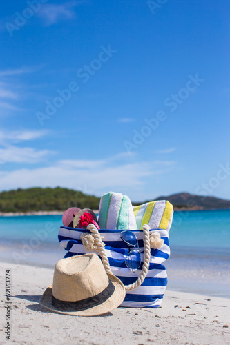 Blue bag, straw hat, flip flops and towel on white tropical