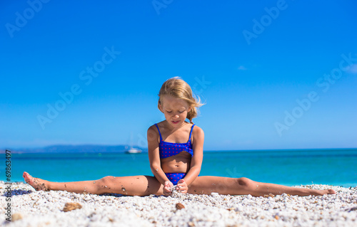 Canvas Print Adorable little girl making leg-split on tropical white sandy