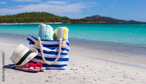 Beach bag, straw hat, flip flops and towel on white tropical