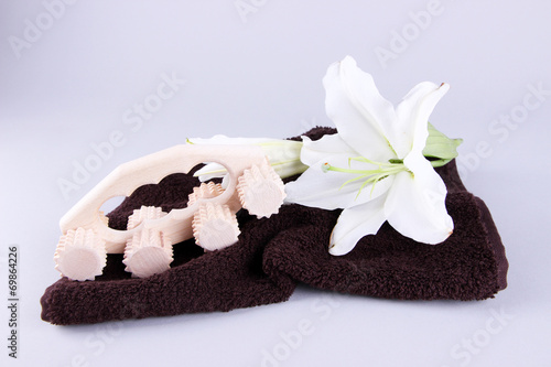 Wooden roller brush  towels and lily on grey background