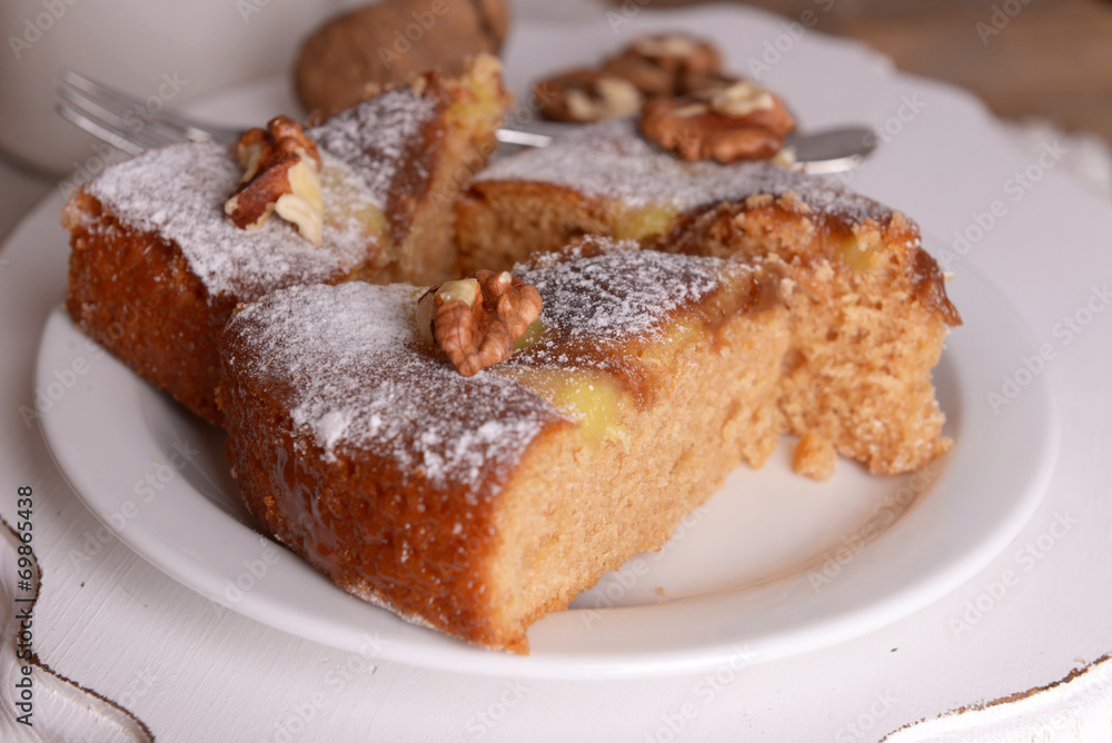Pieces of delicious cake with nuts on plate on wooden table Pieces of delicious cake with nuts on plate on wooden table