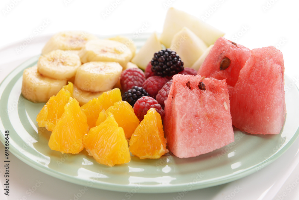 Slices of fruits with berries on plate close up Slices of fruits with berries on plate close up