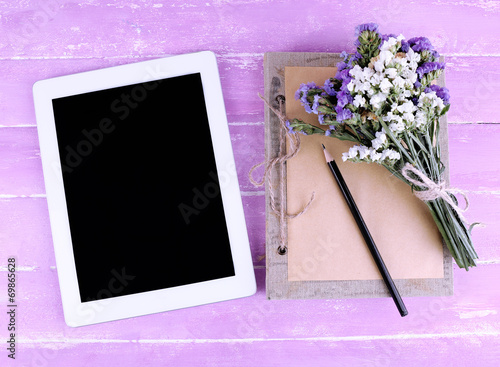 Tablet, notebook, pencil and bunch of field flowers photo