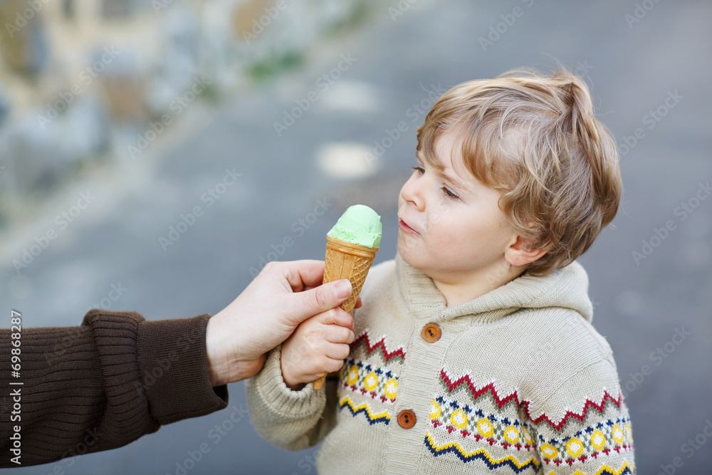 Happy little boy eating ice cream, outdoors Happy little boy eating ice cream, outdoors