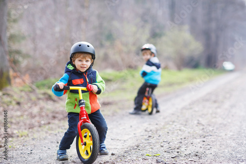 Fototapeta Naklejka Na Ścianę i Meble -  Two active little sibling boys having fun on bikes in forest