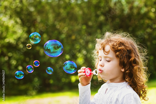 A little girl blowing soap bubbles  closeup portrait beautiful c