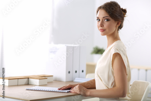 Attractive businesswoman sitting  on desk in the office
