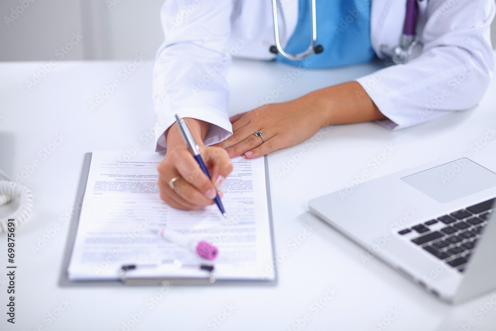 Female doctor sitting on the desk and working a laptop in Female doctor sitting on the desk and working a laptop in