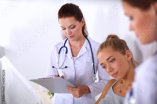 Smiling female doctor with a folder in uniform standing at