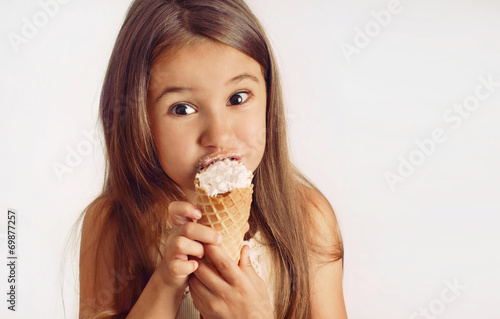 little cute girl having fun with creamy puff on white background