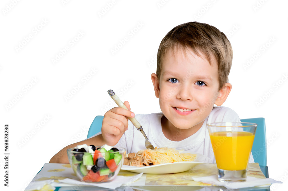 Smiling joyful boy sitting at the dinner table and looking at th Smiling joyful boy sitting at the dinner table and looking at th