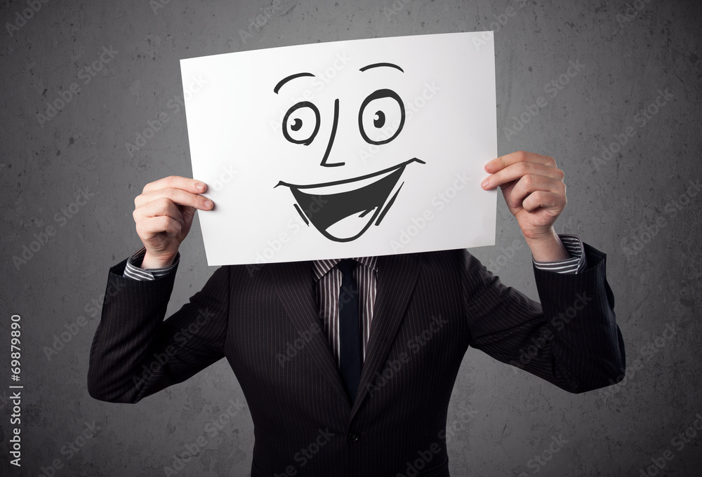Businessman holding a cardboard with smiley face on it in front Businessman holding a cardboard with smiley face on it in front