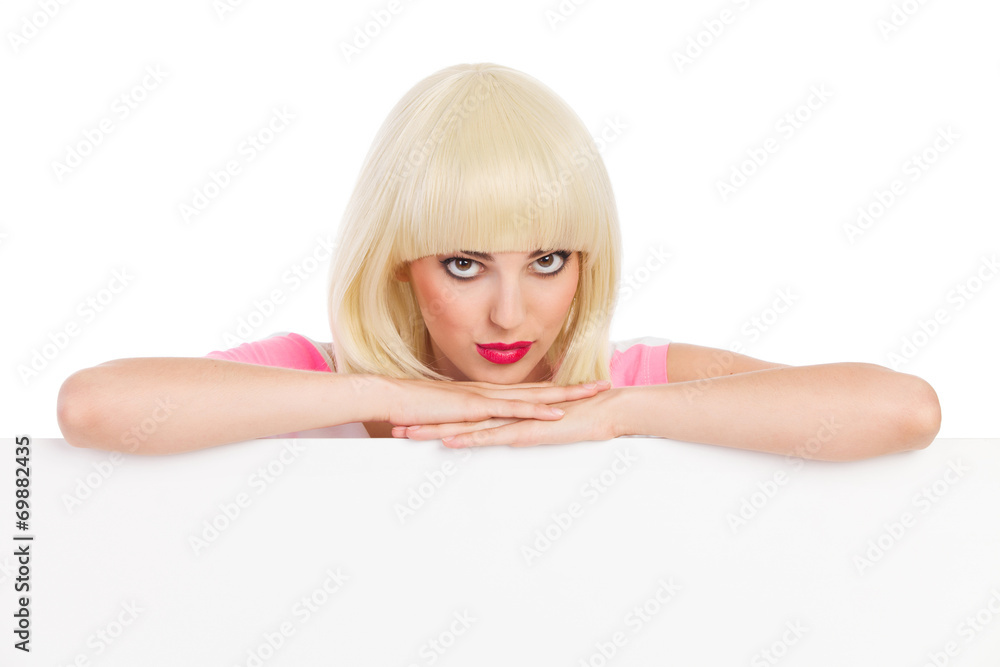 Cheerful blonde girl leaning on a white banner Cheerful blonde girl leaning on a white banner