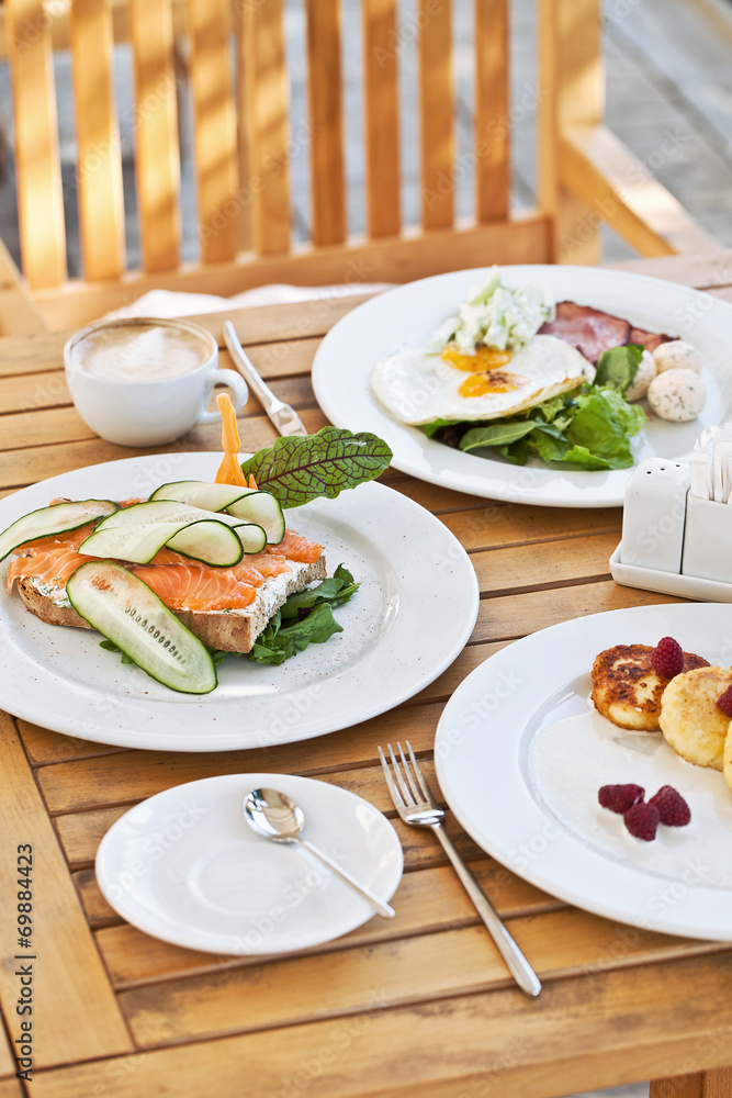 Yummy breakfast. Cheesecakes, Sandwich with Smoked Salmon, Fried Yummy breakfast. Cheesecakes, Sandwich with Smoked Salmon, Fried