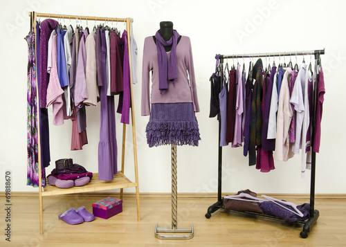Wardrobe with purple clothes on hangers and outfit on mannequin.