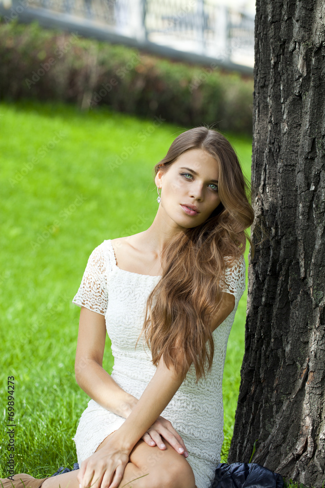 Young pretty girl sitting on green grass