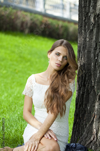 Young pretty girl sitting on green grass