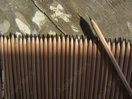 Row of identical pencils on a old wooden background