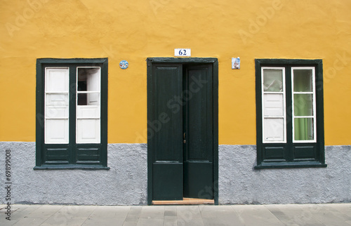door and two windows on yellow wall