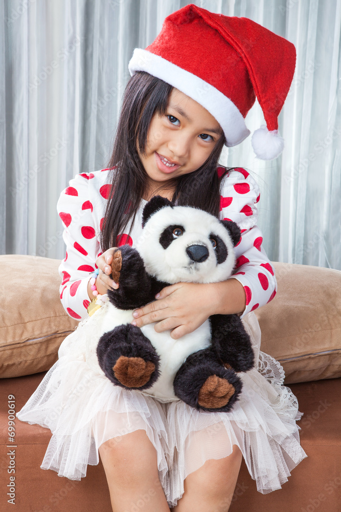 Obraz premium smiling girl in santa helper hat with teddy bear