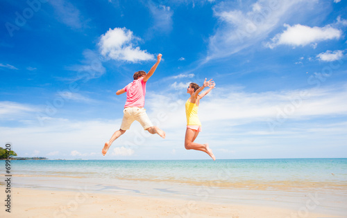 young couple in sunglasses jumping at tropical beach