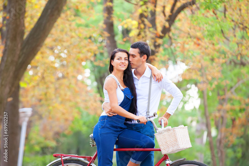 Teen couple with retro bike kissing in the park in autumn time