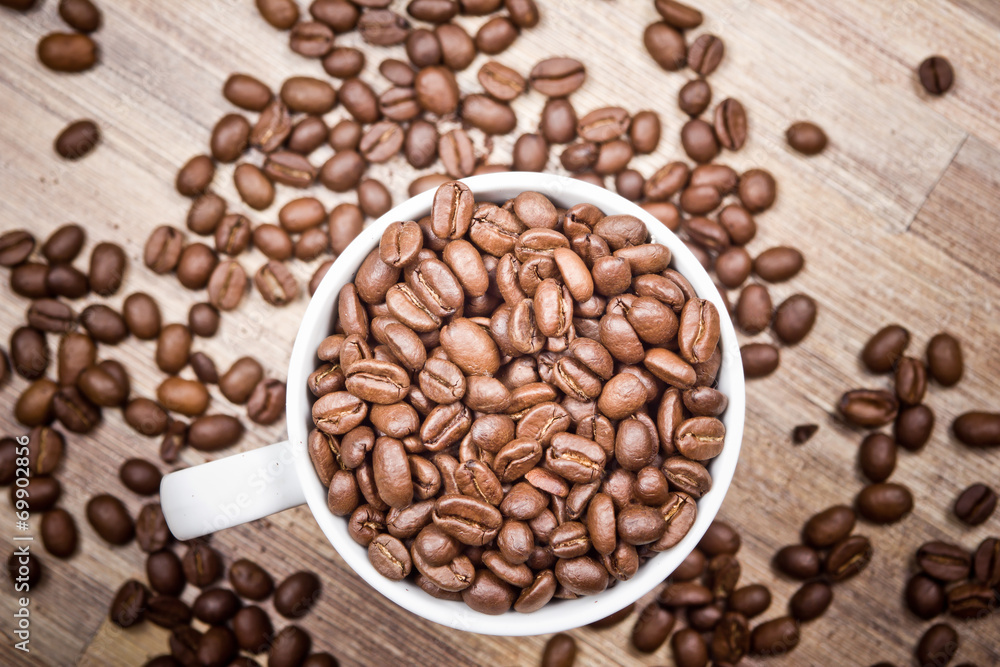 Fototapeta premium White coffee mug filled with coffee seeds.