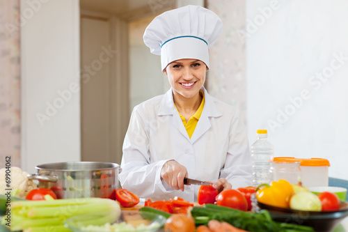  smiling cook works with tomato and other vegetables