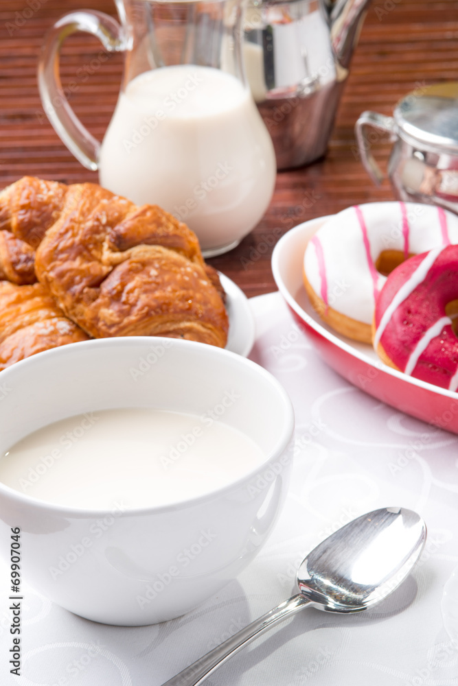 Prima colazione con donuts, brioches e tazza di latte Prima colazione con donuts, brioches e tazza di latte