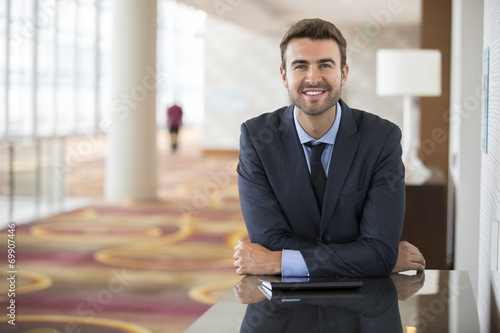 Portrait of happy young businessman waiting in hotel lobby photo