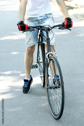 Fototapeta Naklejka Na Ścianę i Meble -  Young man riding bike in city park