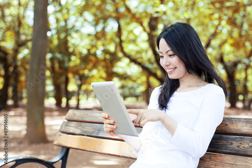 公園のベンチでタブレットPCを使う女性