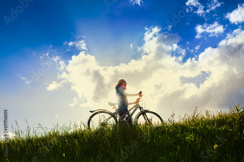 Girl with bike over sky © Sergey Furtaev