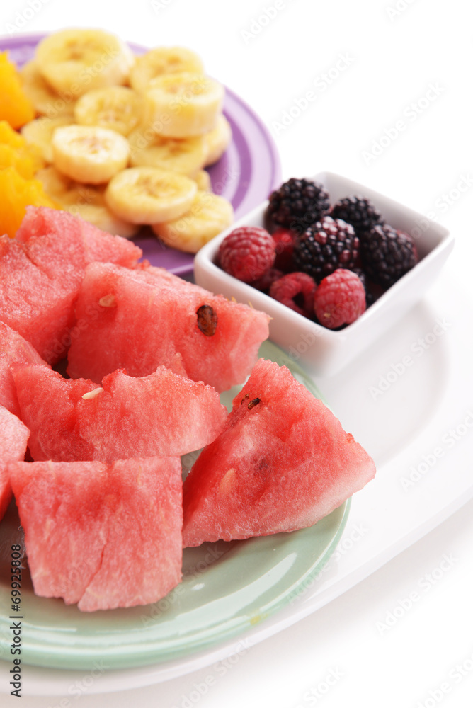 Slices of fruits with berries on plate close up Slices of fruits with berries on plate close up
