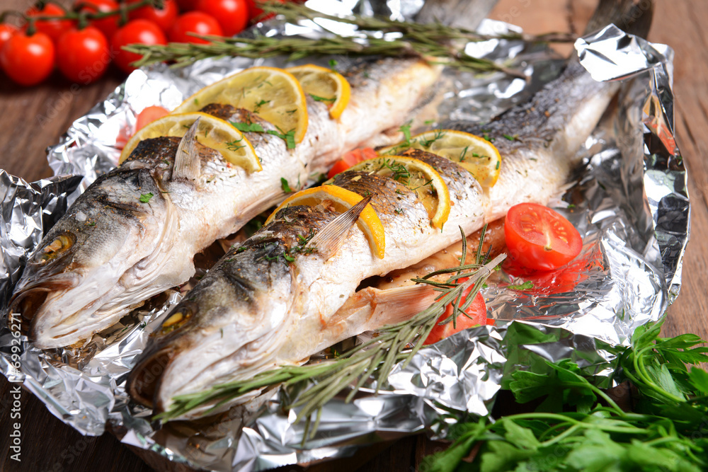 Tasty baked fish in foil on table close-up