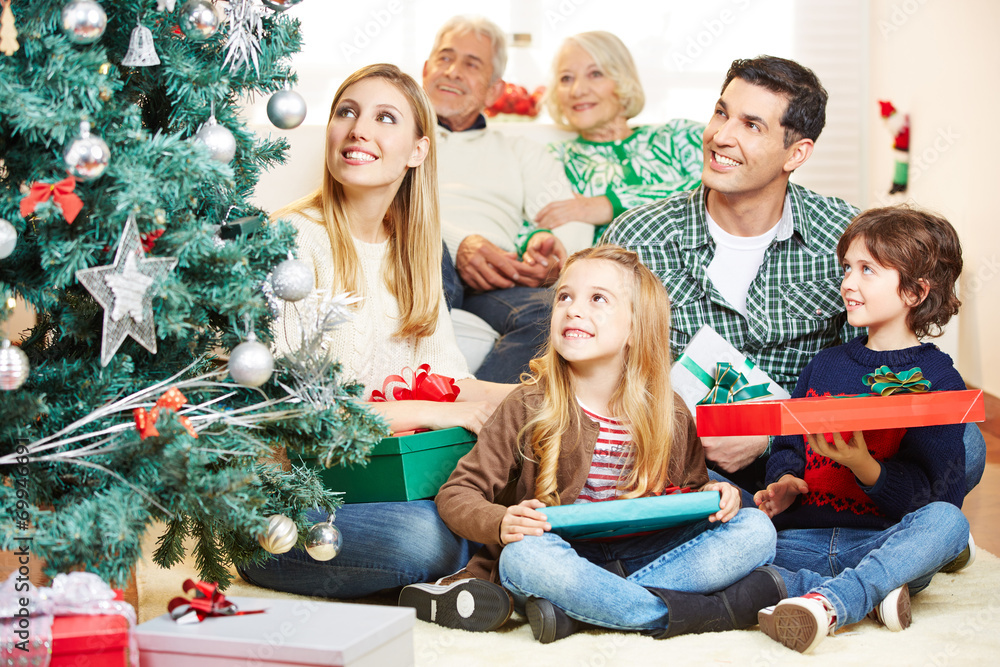 Familie schaut auf Weihnachtsbaum zu Weihnachten Familie schaut auf Weihnachtsbaum zu Weihnachten