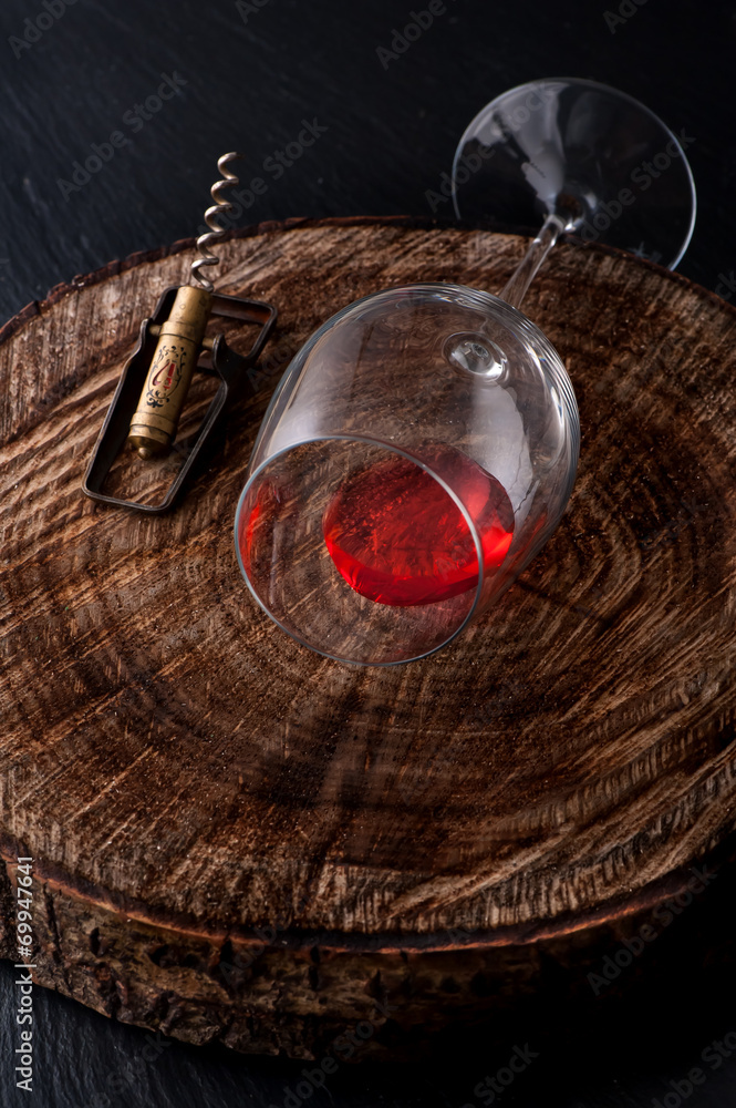 Glass red wine and  corkscrew on dark background
