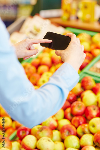 Hand scannt Informationen mit Smartphone im Supermarkt