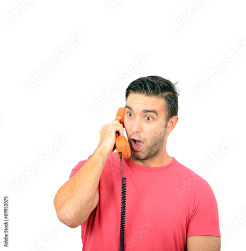 Portrait of young man in shock while talking on phone having unp photo