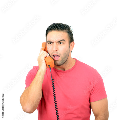 Portrait of young man in shock while talking on phone having unp photo