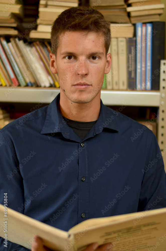 Young man reading a book in the library Young man reading a book in the library